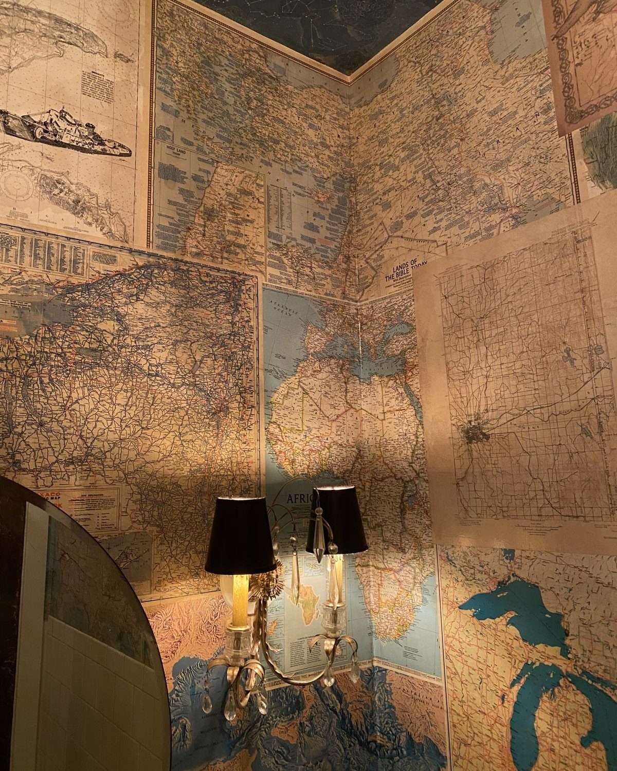 9 Bathroom Mural Ideas for Every Style and Space 5 Vintage historical maps covering the walls of a room with a classic wall lamp.