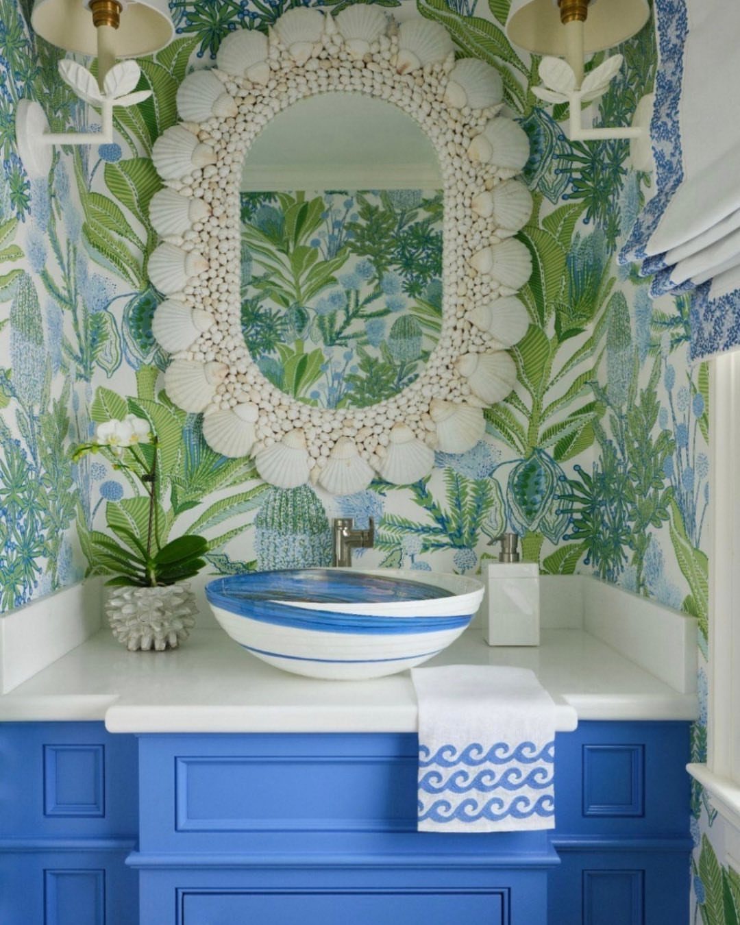9 Bathroom Mural Ideas for Every Style and Space 3 Bathroom with botanical wallpaper, seashell-framed mirror, and a bright blue vanity cabinet.
