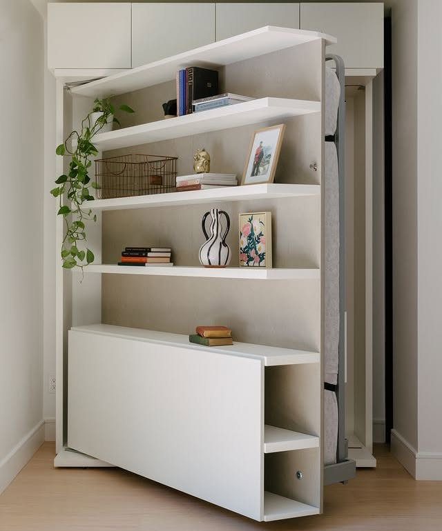White Murphy bed unit with integrated shelving and storage in a modern room
