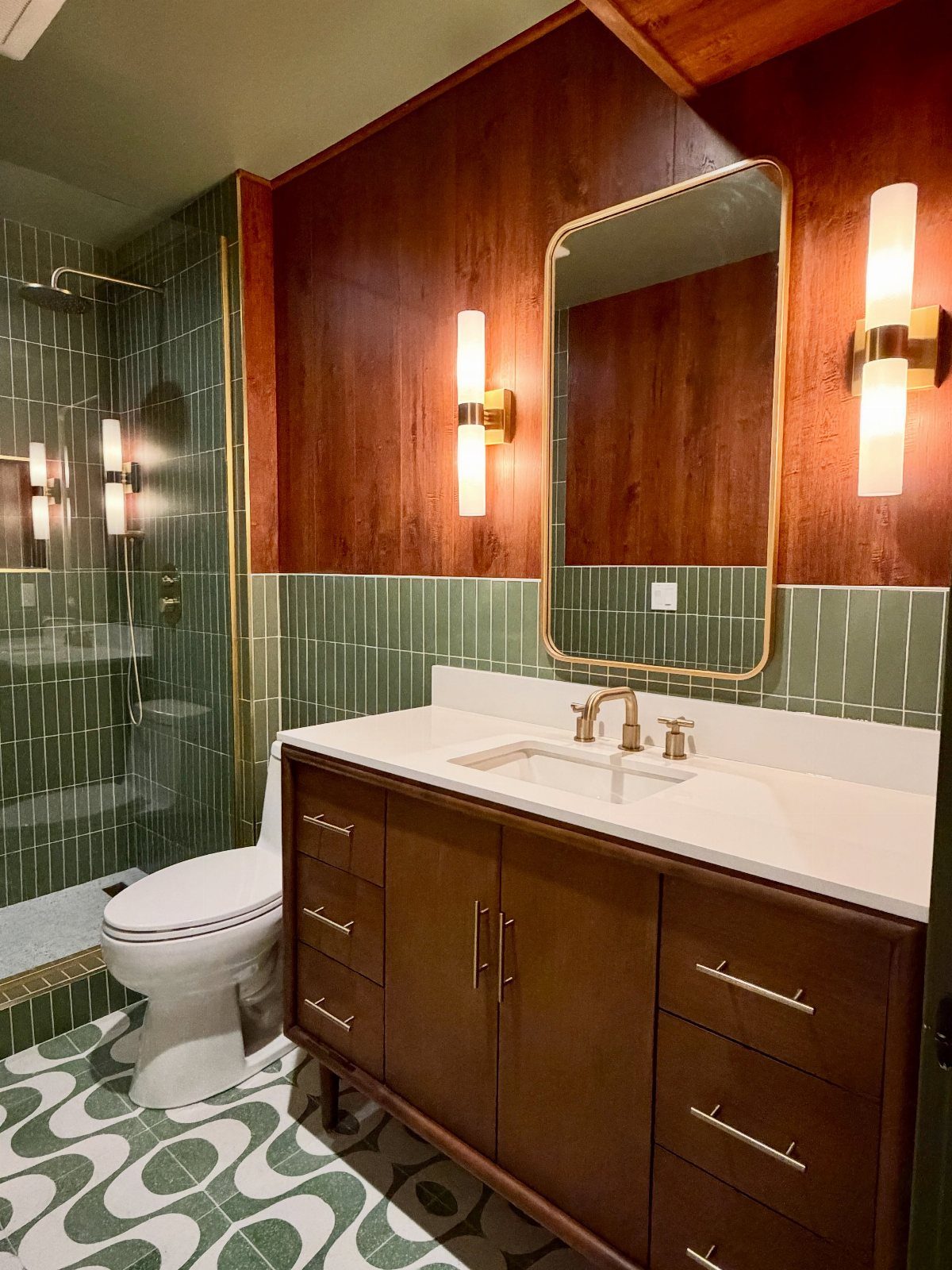 Green and white geometric patterned floor tiles in a mid-century modern bathroom.