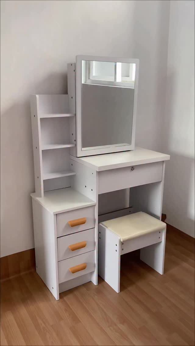 White dressing table with mirror, three drawers, open shelving, and a cushioned stool.