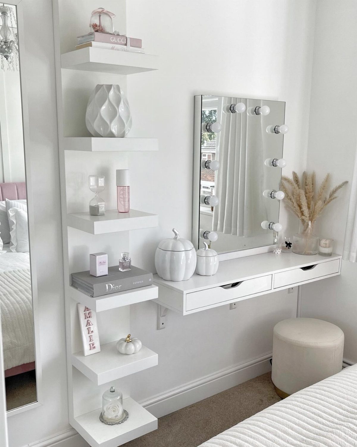 White floating dressing table with a lighted mirror and vertical storage shelves beside it.